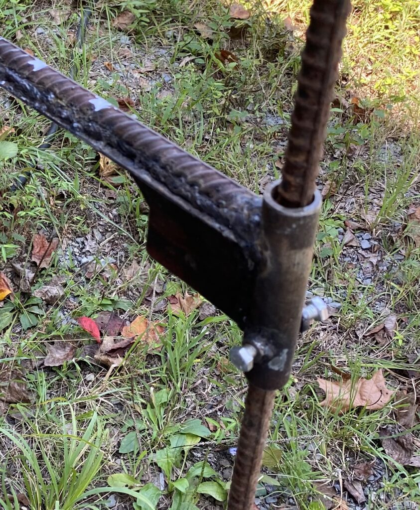 Close-up of the arm bracket where the rebar swing arm attaches to a collar on the post, with two adjustment bolts