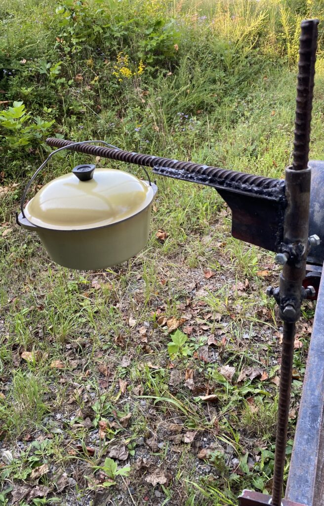 Finished cooking stand holding a yellow enamel pot on its swing arm
