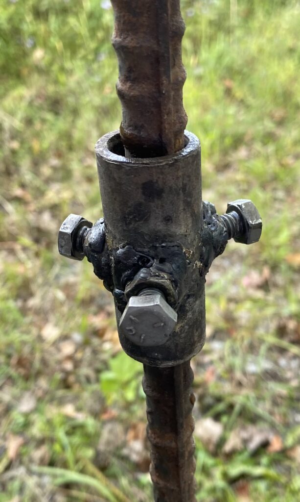 Steel collar on the rebar post with bolts welded in place, which stops the arm from swiveling